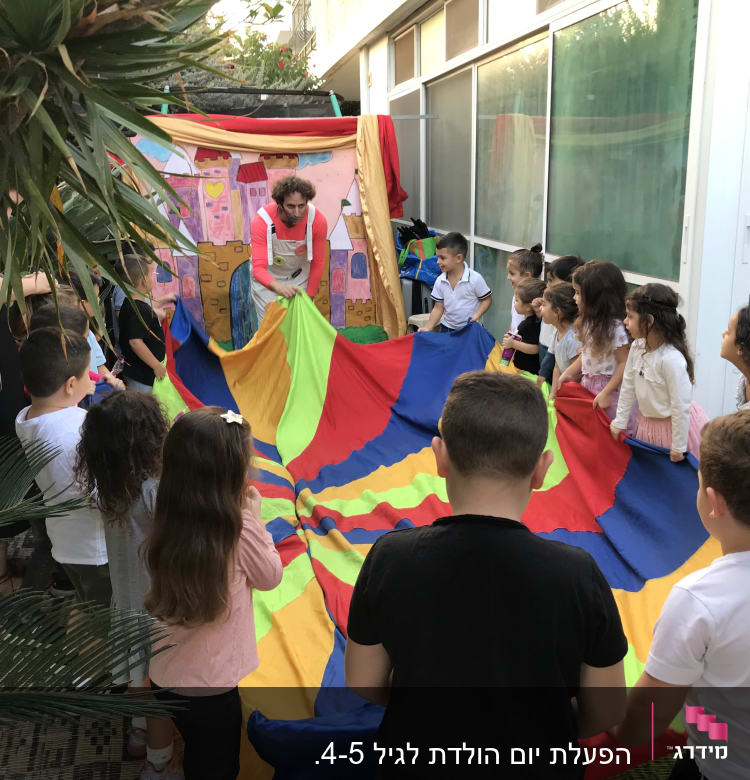 ילדים משחקים עם מצנח צבעוני במסיבת יום הולדת